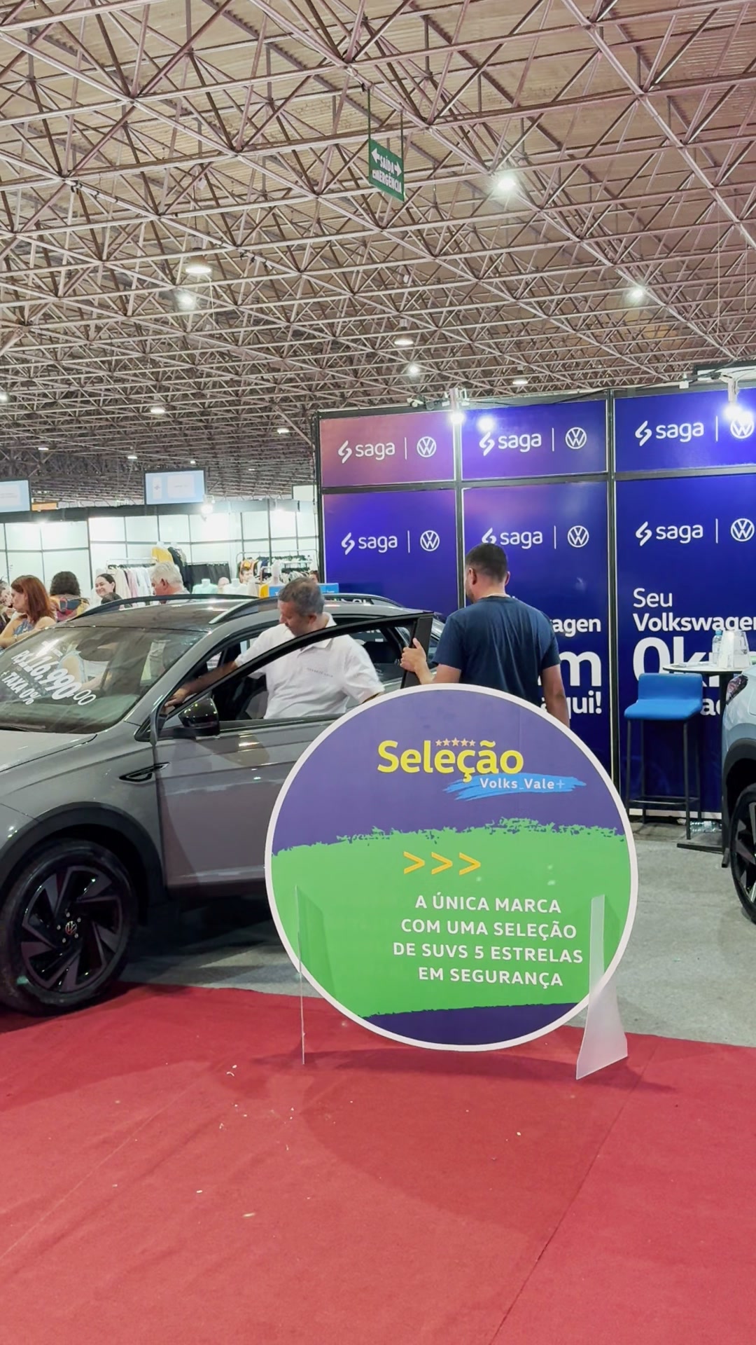 Dois veículos Volkswagen posicionados diante do painel da concessionária Saga.