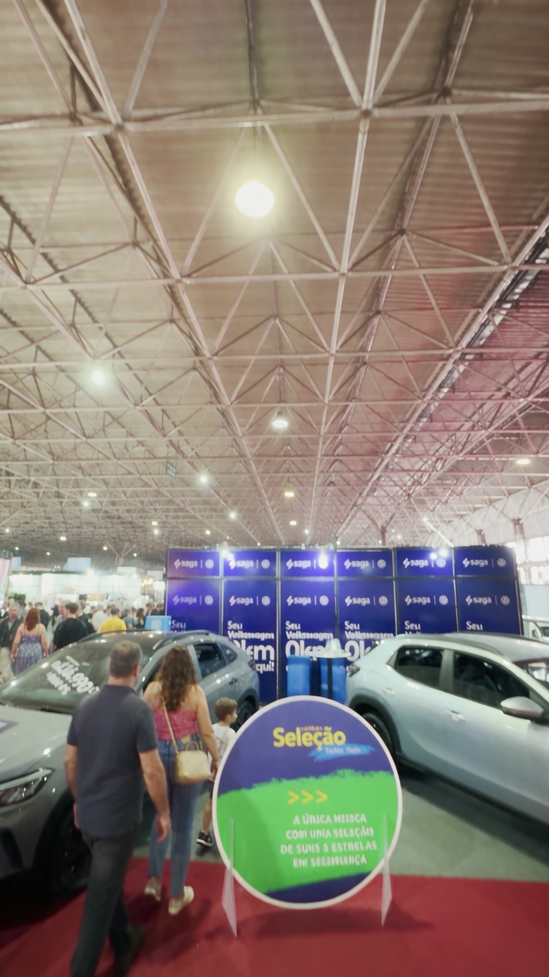 Pavilhão de Exposições lotado visto do alto, com público circulando entre os veículos do estande.